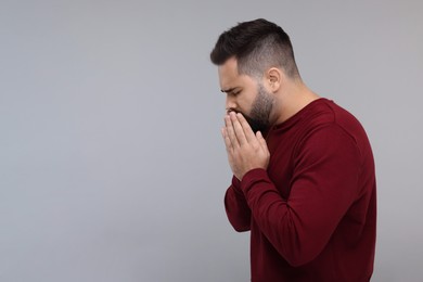 Photo of Sick man coughing on gray background, space for text