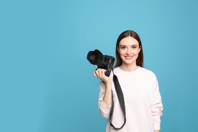 Professional photographer with modern camera on light blue background