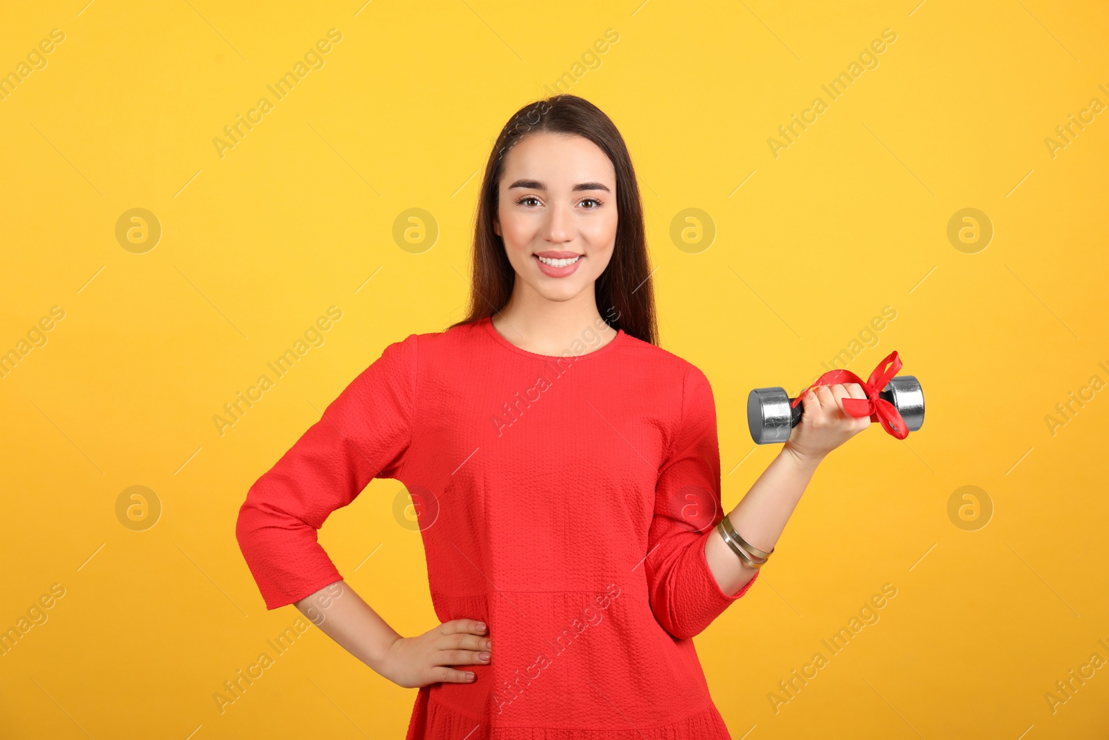 Photo of Woman with dumbbell as symbol of girl power on yellow background. 8 March concept