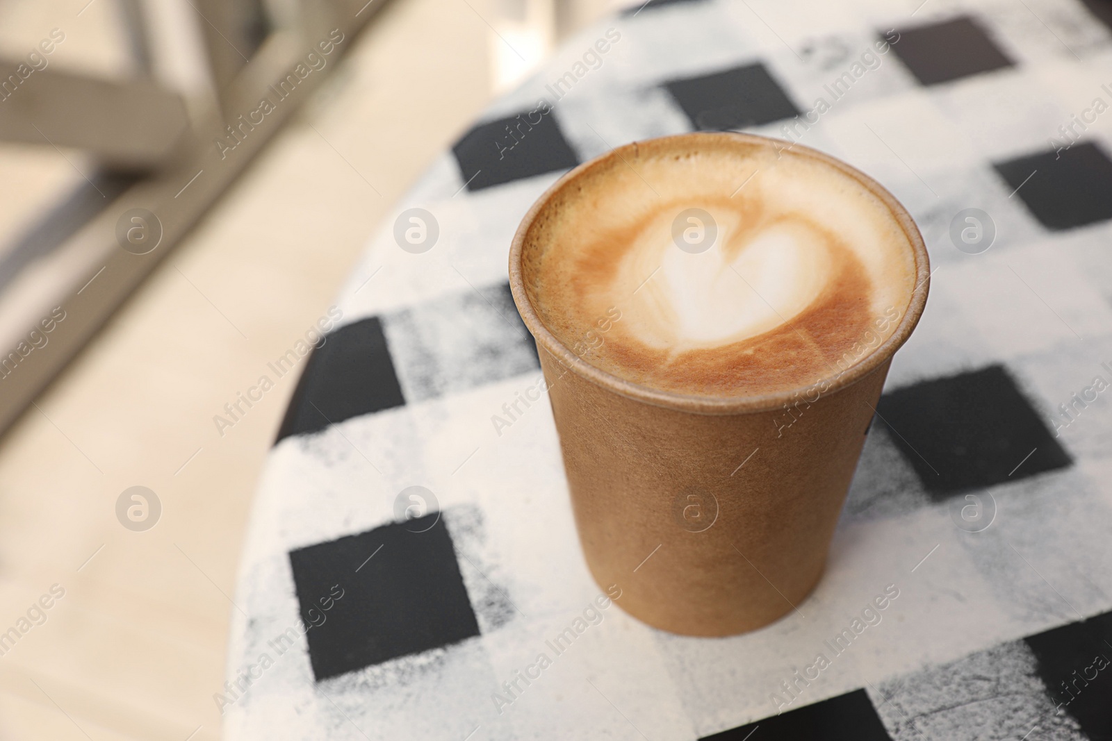 Photo of Takeaway paper cup with hot coffee on table outdoors, space for text