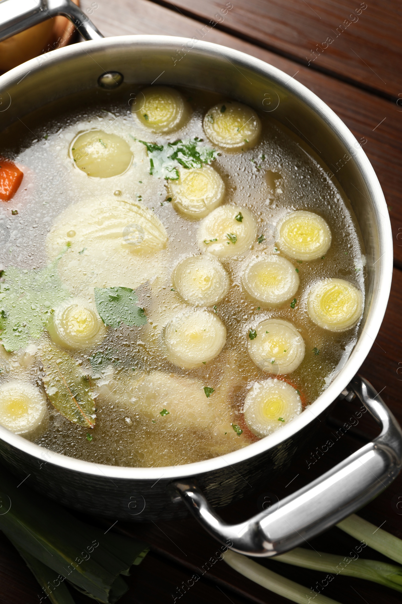 Photo of Pot with tasty bouillon on wooden table, above view