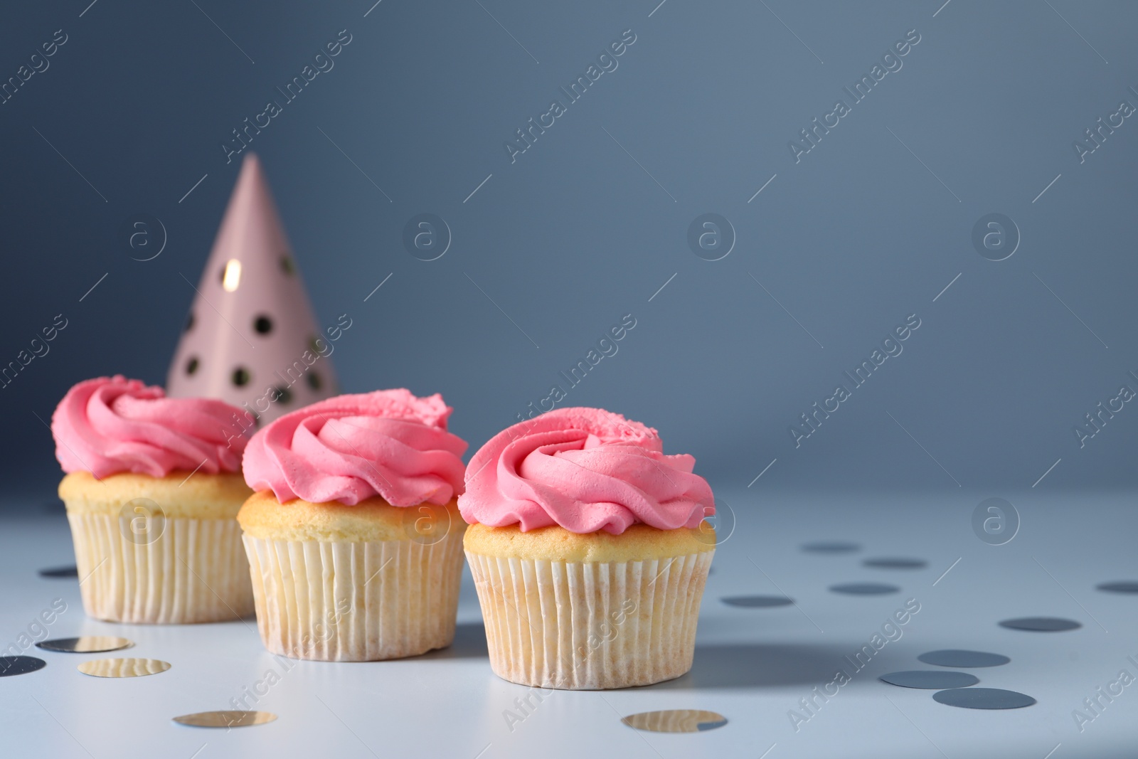 Photo of Delicious cupcakes with bright cream and confetti on light background, space for text