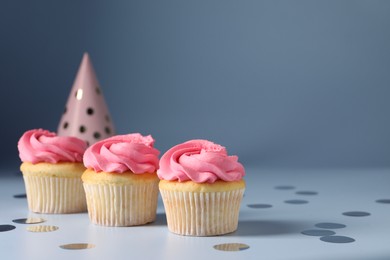 Photo of Delicious cupcakes with bright cream and confetti on light background, space for text