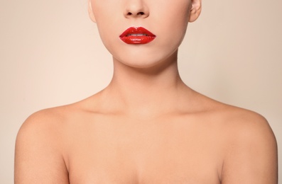 Photo of Beautiful young woman with red glossy lips on color background, closeup