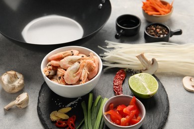 Different products and black wok on grey table, closeup