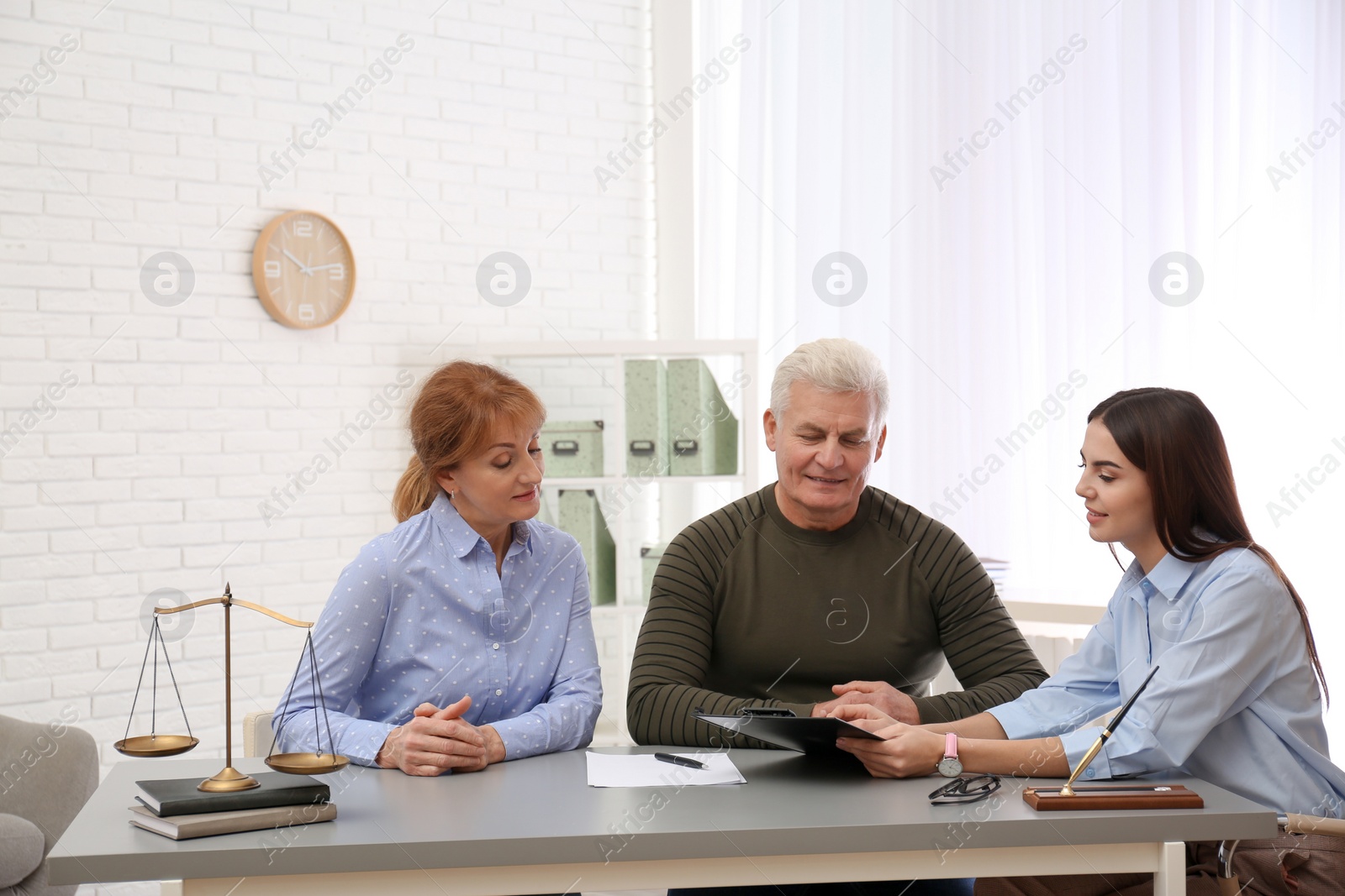 Photo of Young lawyer consulting senior couple in office