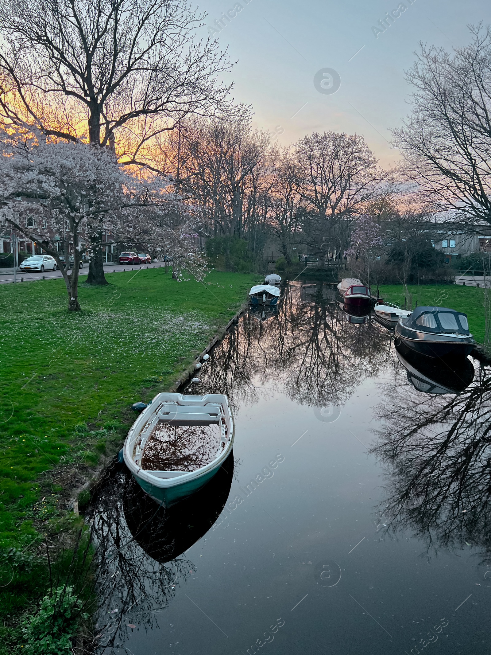 Photo of Canal with moored boats outdoors. Sky reflecting in water