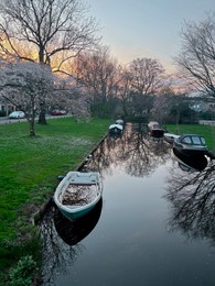 Photo of Canal with moored boats outdoors. Sky reflecting in water