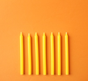 Yellow birthday candles on orange background, top view