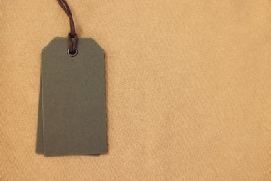 Photo of Cardboard tags on beige garment, top view. Space for text