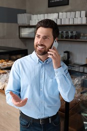 Happy business owner talking on phone in bakery shop