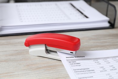 Stapler with document on wooden table, closeup