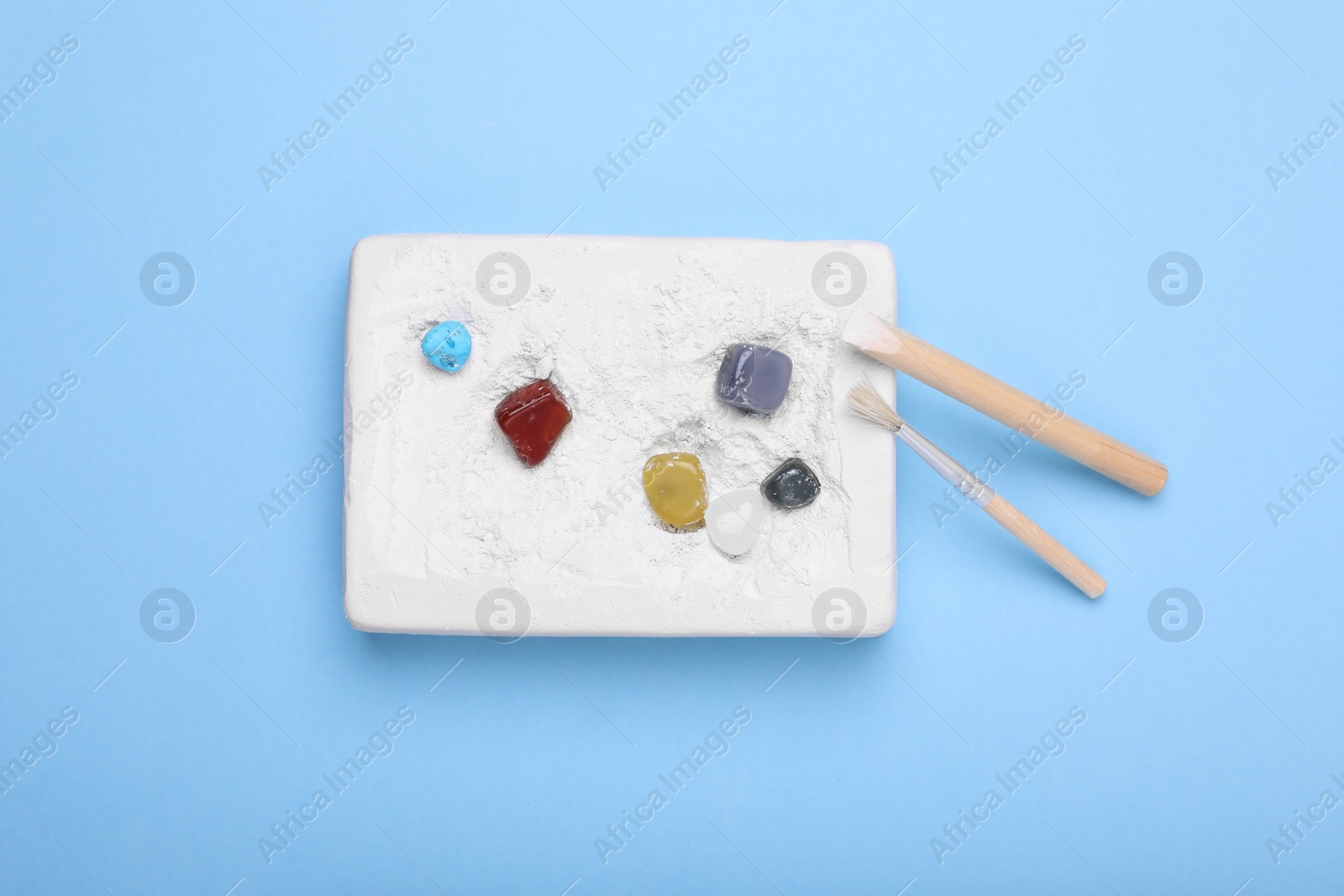 Photo of Excavation kit on light blue background, top view. Educational toy for motor skills