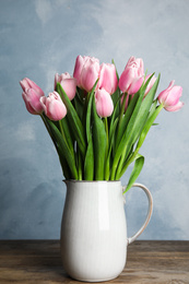 Photo of Beautiful pink spring tulips in vase on wooden table