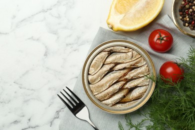 Tin can with tasty sprats served on white marble table, flat lay. Space for text