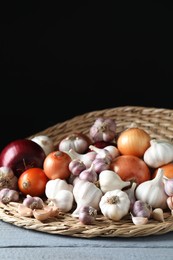 Photo of Fresh raw garlic and onions on gray wooden table against black background. Space for text