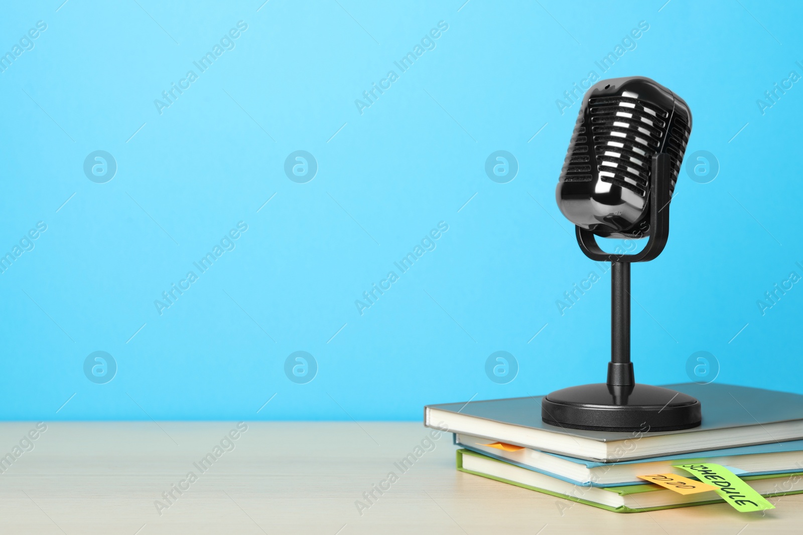 Photo of Retro microphone and notebooks on wooden table against light blue background, space for text. Job interview