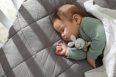Photo of Cute little baby sleeping in crib at home. Space for text