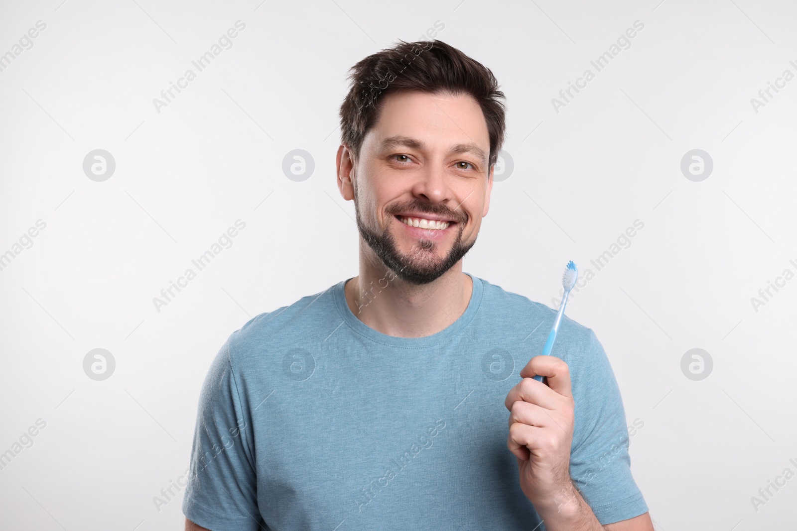 Photo of Happy man holding plastic toothbrush on white background. Mouth hygiene