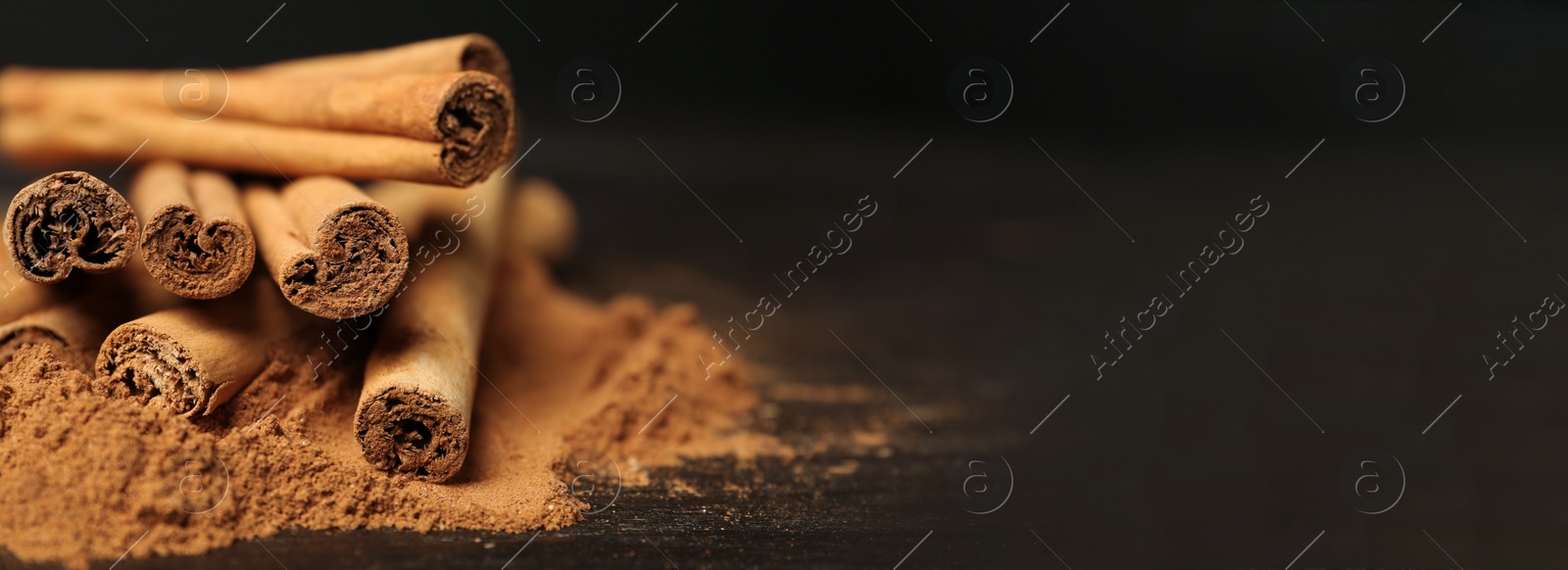 Image of Aromatic cinnamon sticks and powder on table, closeup view with space for text. Banner design