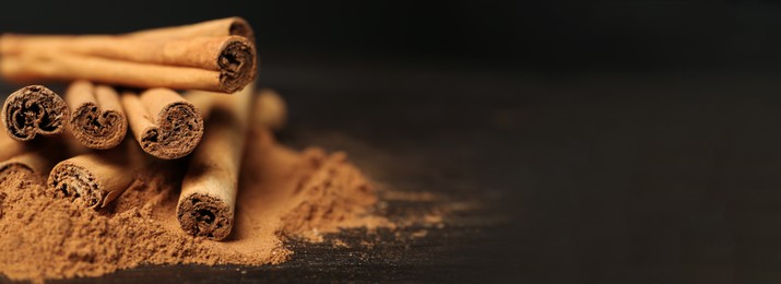 Image of Aromatic cinnamon sticks and powder on table, closeup view with space for text. Banner design