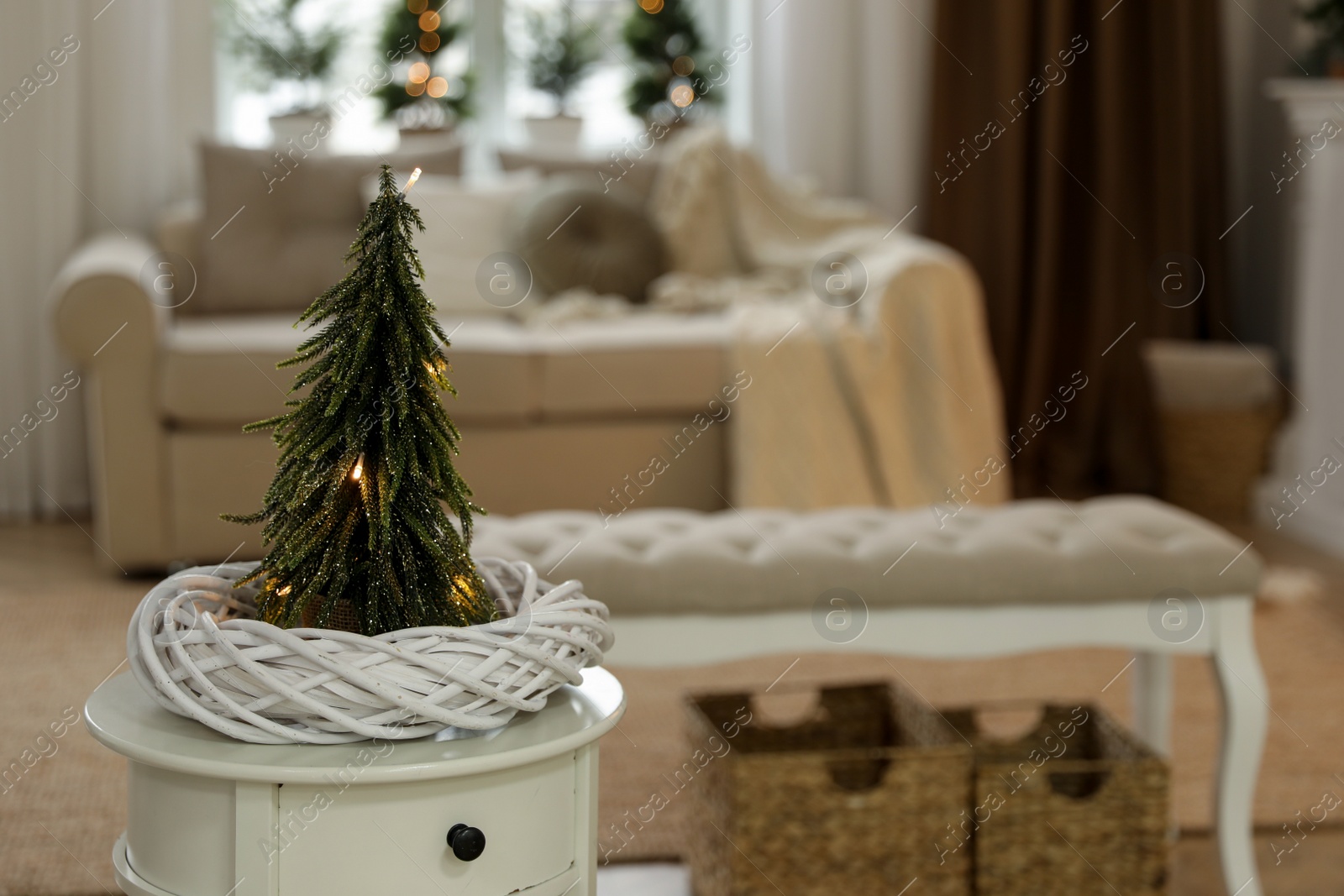 Photo of Small decorative Christmas tree on white table in living room. Interior design