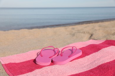 Photo of Beach towel and slippers on sand near sea