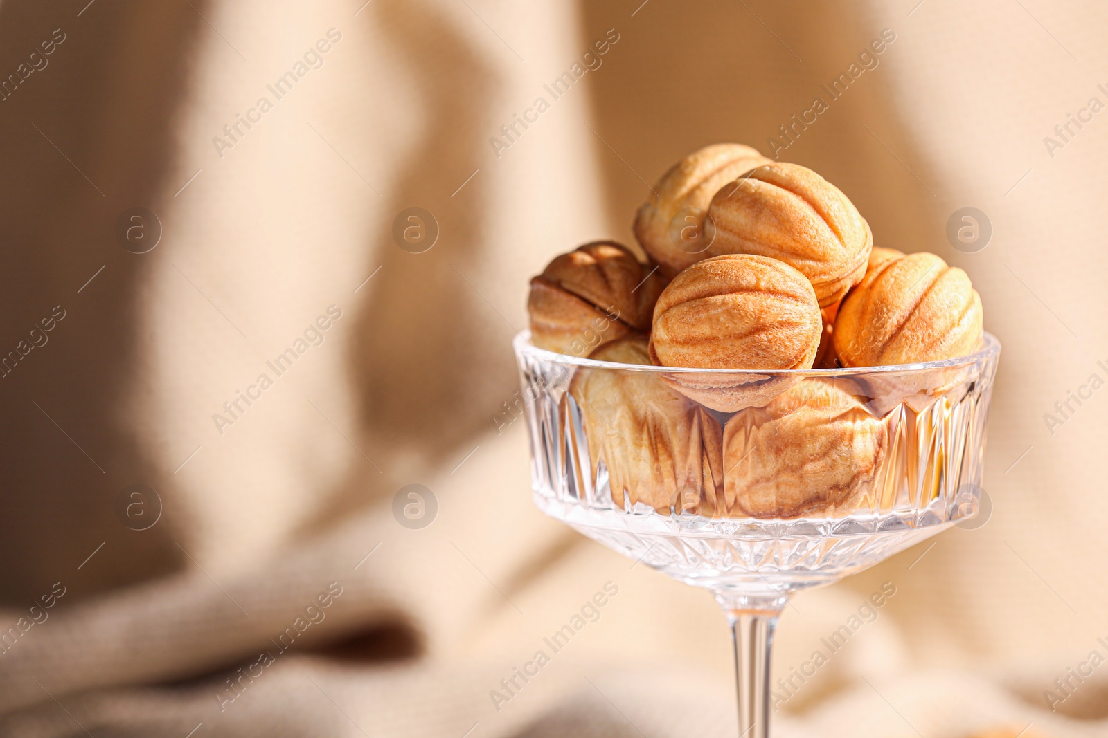 Photo of Delicious nut shaped cookies in glass holder on blurred background, closeup. Space for text