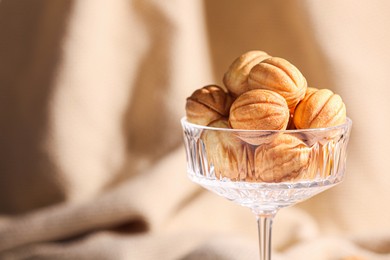 Photo of Delicious nut shaped cookies in glass holder on blurred background, closeup. Space for text