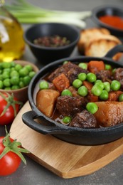 Photo of Delicious beef stew and ingredients on grey table