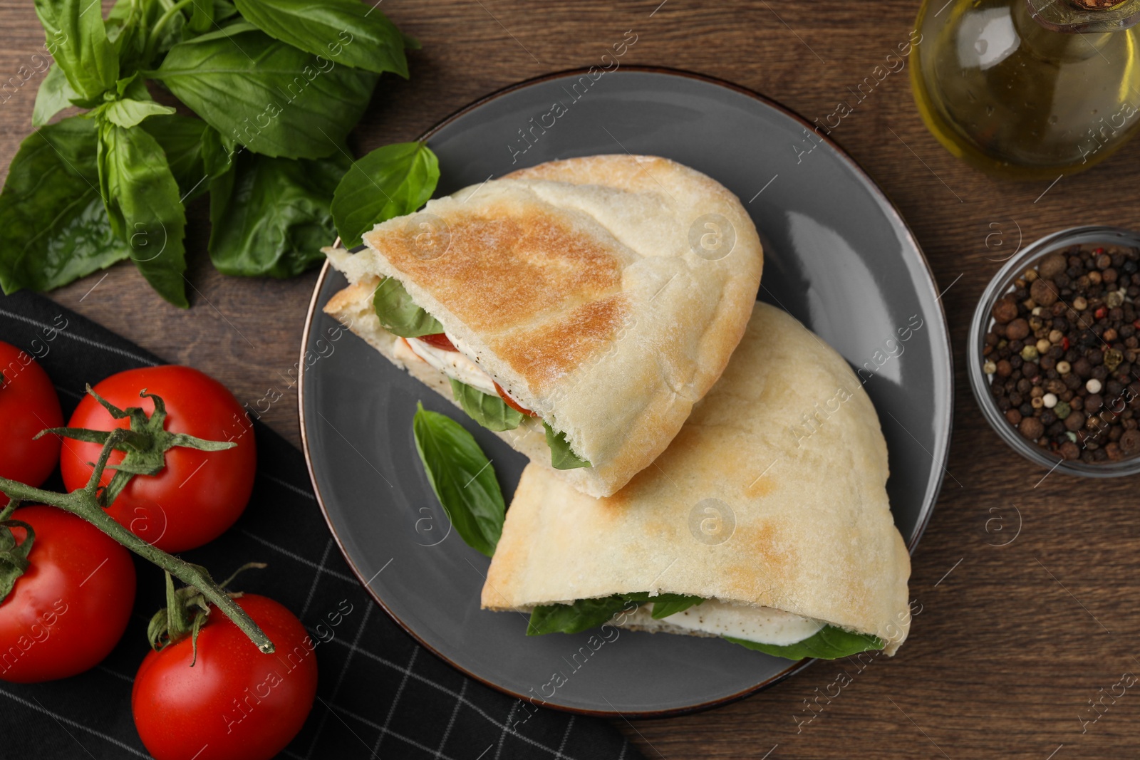 Photo of Delicious pita sandwiches with mozzarella, tomatoes and basil on wooden table, flat lay