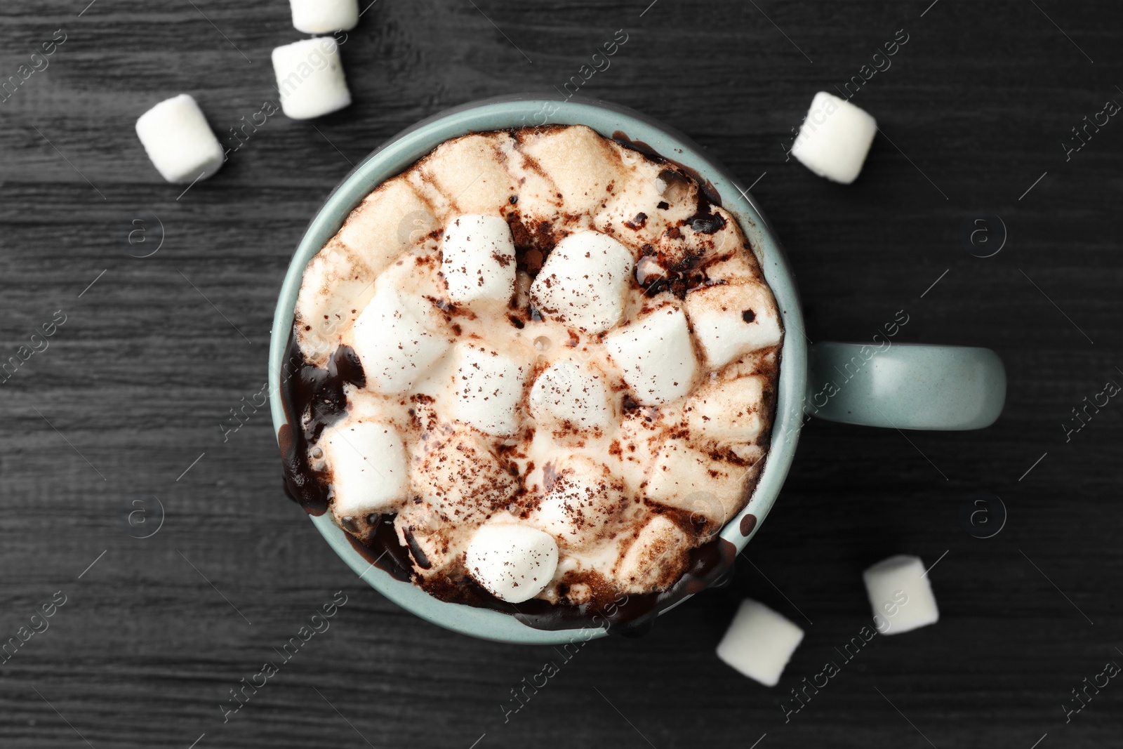 Photo of Cup of aromatic hot chocolate with marshmallows and cocoa powder on dark gray wooden table, top view