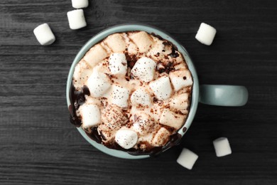 Cup of aromatic hot chocolate with marshmallows and cocoa powder on dark gray wooden table, top view