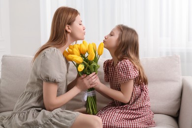 Photo of Daughter congratulating mom with bouquet of yellow tulips at home