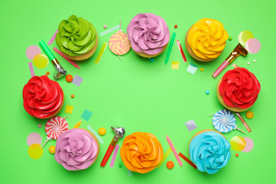 Photo of Flat lay composition with colorful birthday cupcakes on green background. Space for text