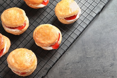 Tasty scones with clotted cream and jam on cooling rack, top view