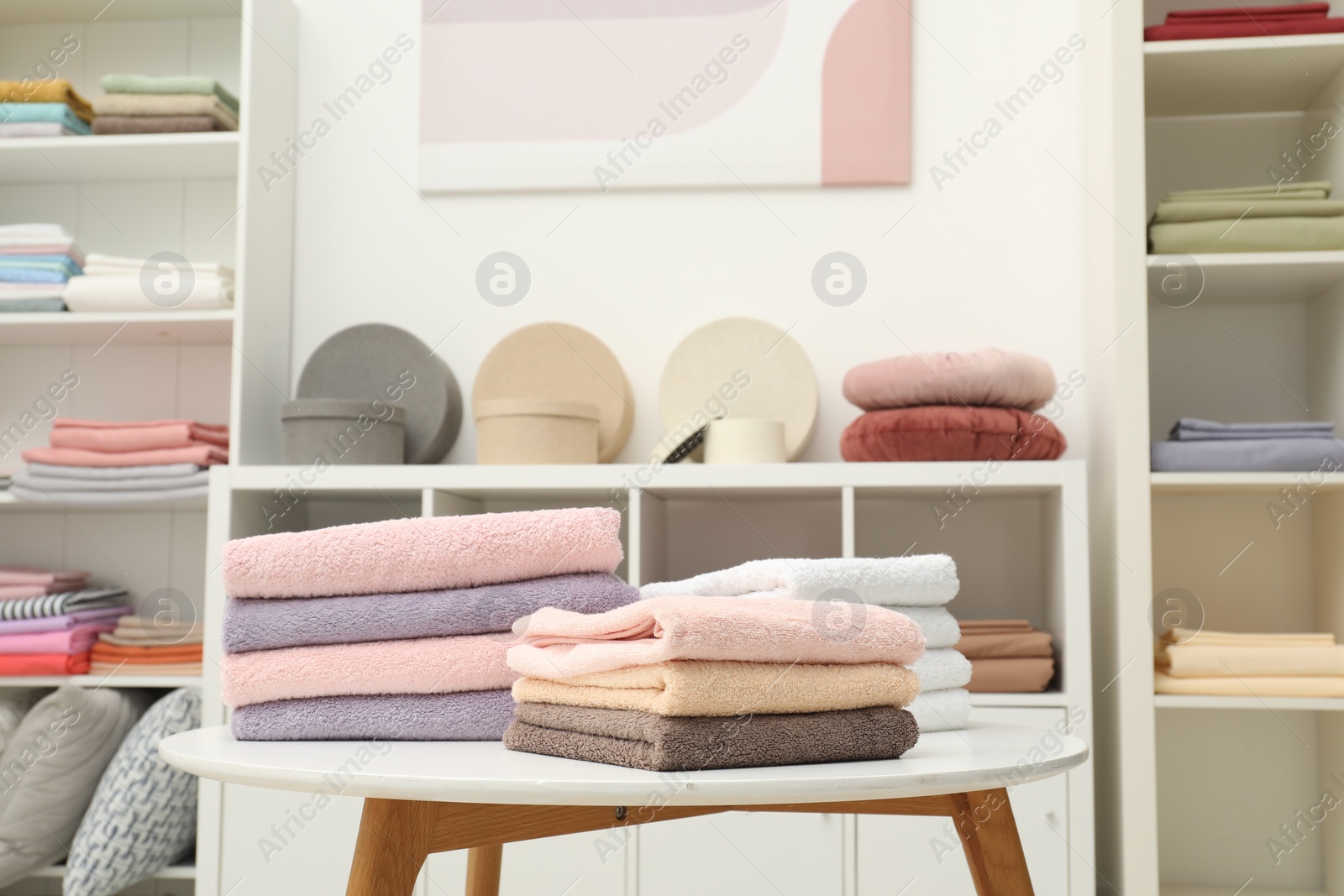 Photo of Stacked towels, decorative boxes and colorful bed linens in shop