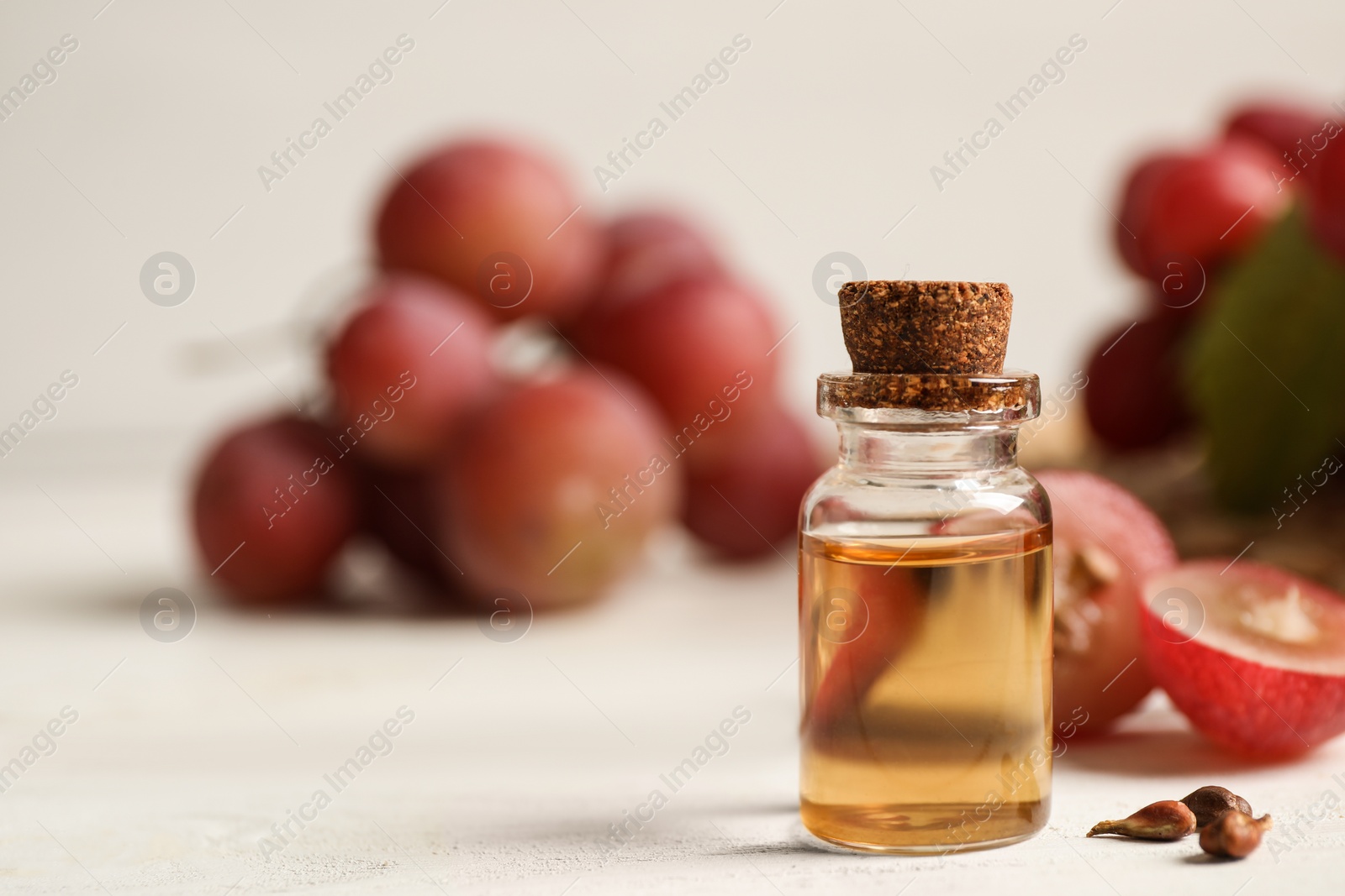 Photo of Bottle of natural grape seed oil on white wooden table, space for text. Organic cosmetic