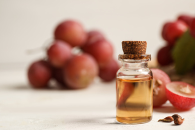 Bottle of natural grape seed oil on white wooden table, space for text. Organic cosmetic