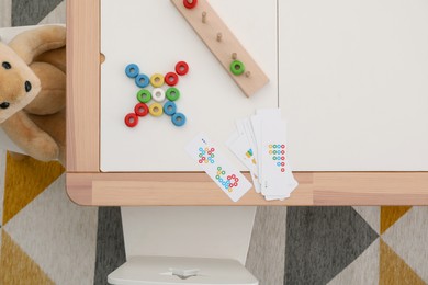 Photo of Stacking and counting game on table and teddy bear indoors, flat lay. Educational toy for motor skills development