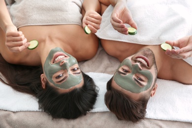 Photo of Happy couple enjoying facial treatment procedure in spa salon, above view