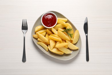 Photo of Plate with tasty baked potato wedges, rosemary and sauce on white wooden table, flat lay