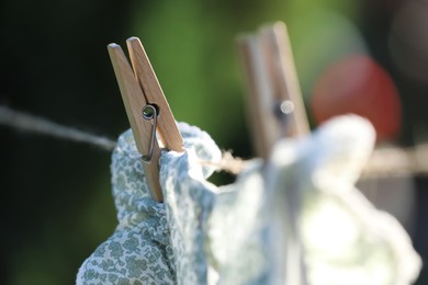 Photo of Washing line with drying dress against blurred background, focus on clothespin