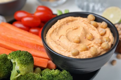 Plate with delicious hummus and fresh vegetables on white table, closeup