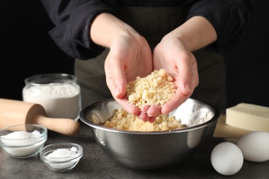 Woman with shortcrust pastry at grey table, closeup