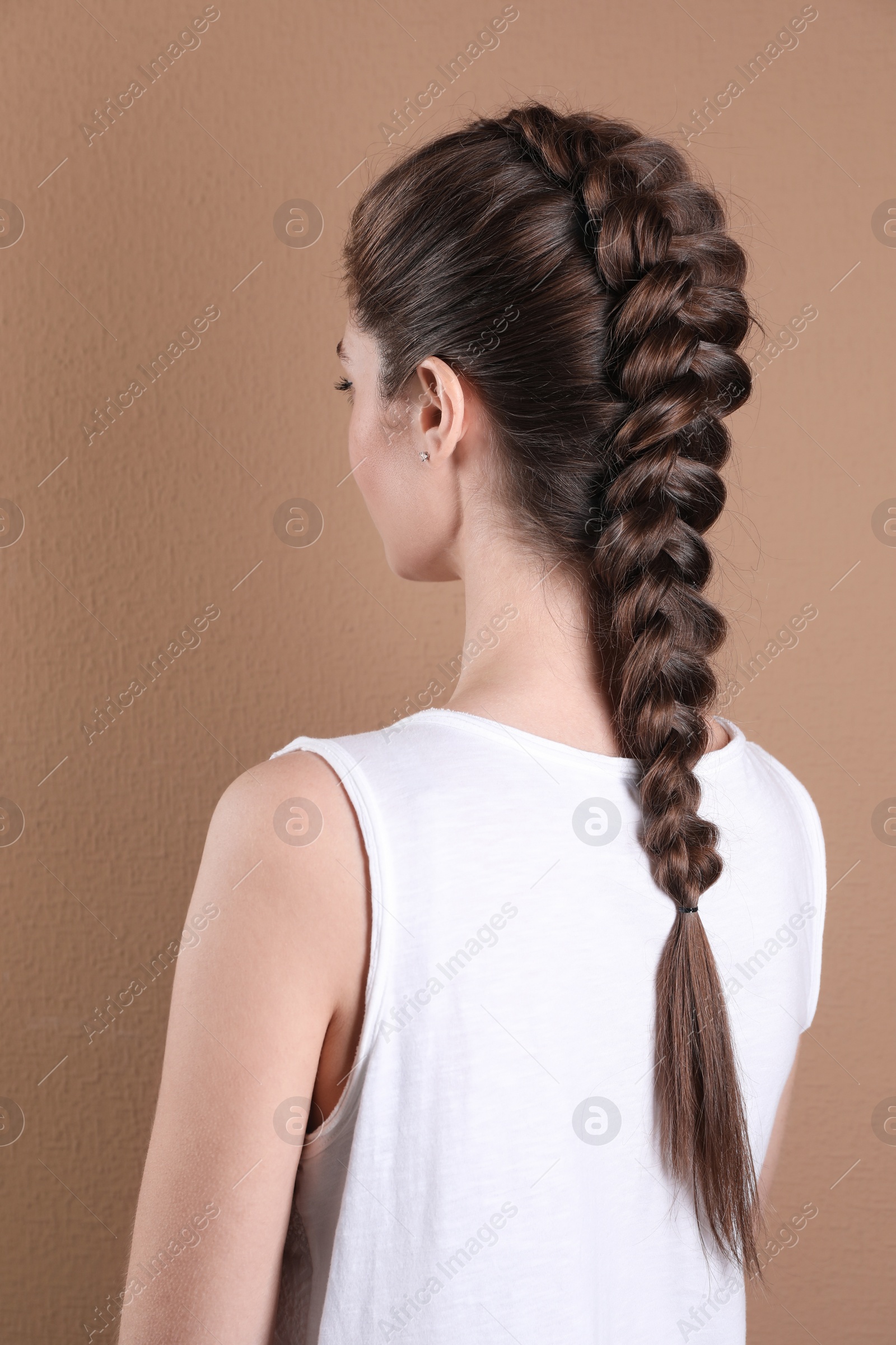 Photo of Woman with braided hair on light brown background, back view