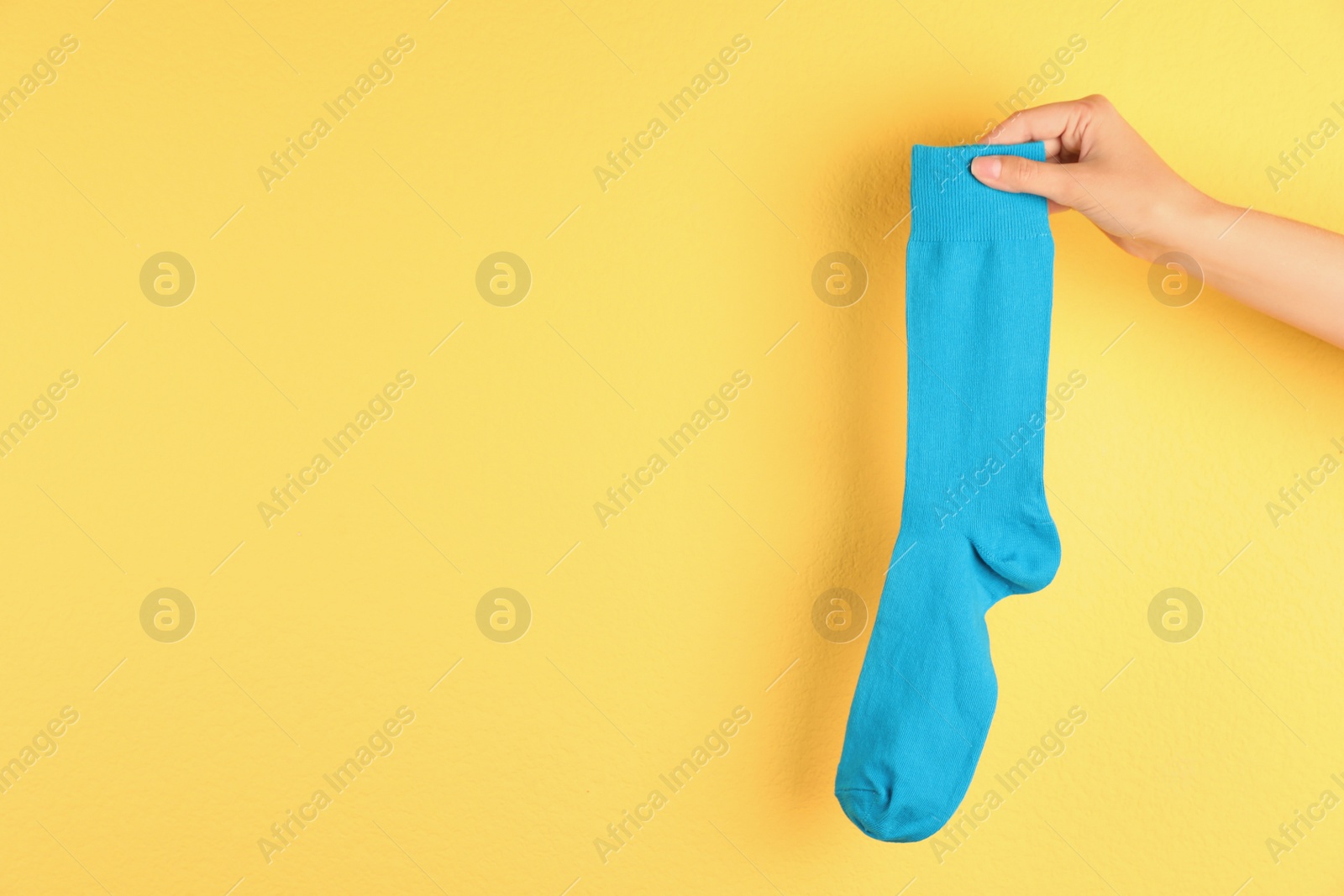 Photo of Woman holding bright sock and space for design on color background