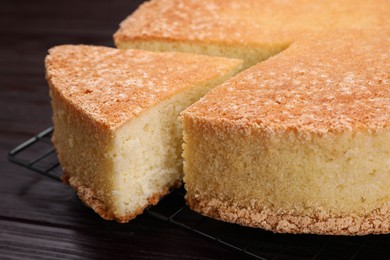 Photo of Tasty sponge cake on wooden table, closeup