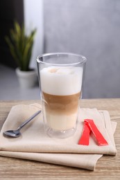 Photo of Delicious coffee in glass and sugar packets on wooden table