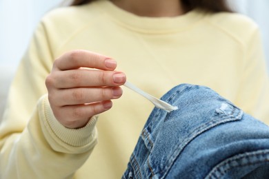 Woman removing chewing gum from jeans, closeup